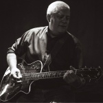 Either dim-lighting or black and white image of Dave Sadler playing guitar. Credit: John David Pittman