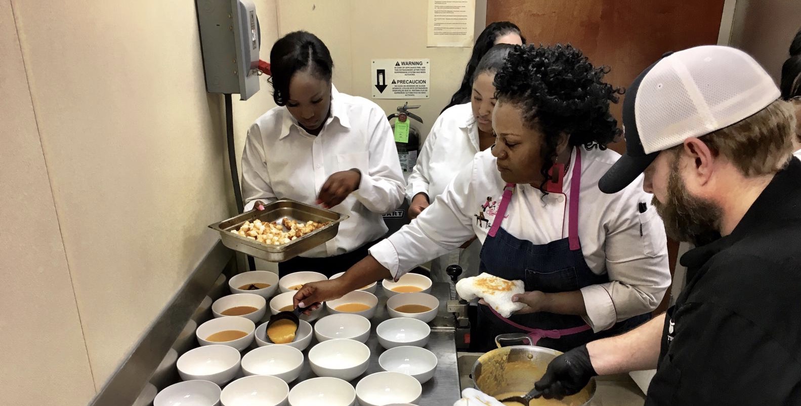 Chef Jennifer Hill Booker and Chef Rob Nelson (foreground) prepare pumpkin soup while their team adds finishing touches at the Inaugural Chef’s Dinner held by the Front Porch Hospitality Group. Credit: Charity Stephens
