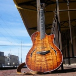 Dave Sadler’s hollow body electric guitar, positioned vertically against a guitar stand. Visit davesadlermusic.com for more.